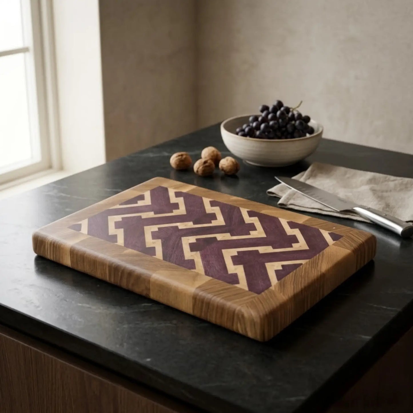 Wooden cutting board with geometric pattern on a kitchen counter with grapes and nuts.